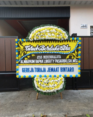 Papan Bunga Duka di Kepala Madan