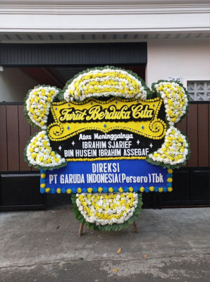 Papan Bunga Duka di Kepala Madan
